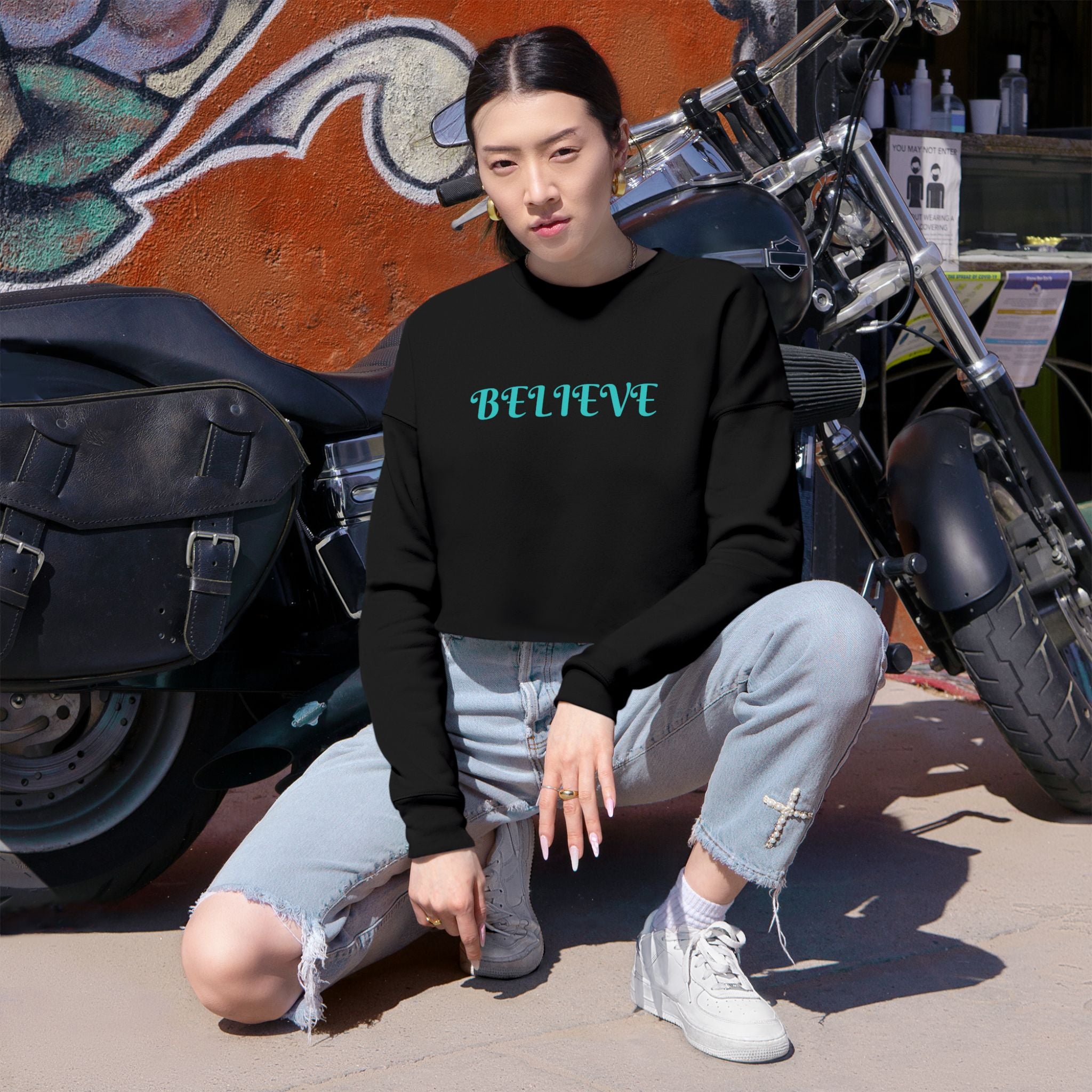 Believe Cropped Sweatshirt — Women's Black Graphic Crop Top with Turquoise 'BELIEVE' Text